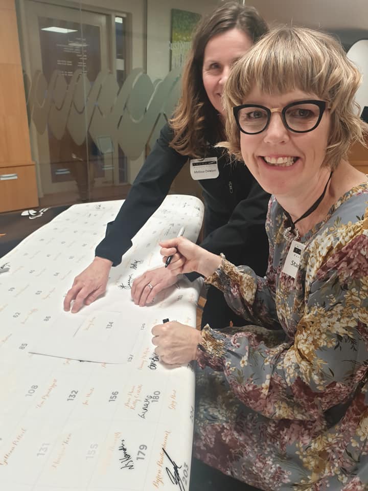 Stacey signing the giant poster with signature of all NZ Paralympians