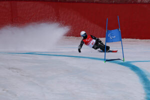 A sit skier flies around the flags