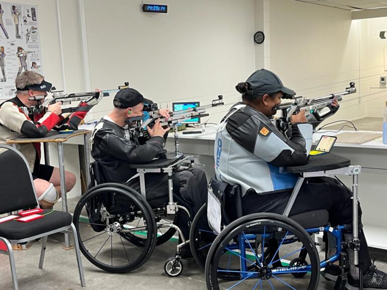 Greg, Mike and Neelam take aim with rifles in an indoor shooting range